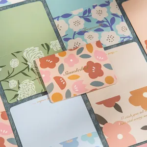 Detalle de tarjetas de felicitación florales en acuarela con texto dorado elegante