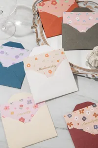 Vue détaillée de cartes de vœux florales avec texte doré et enveloppes colorées