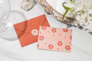 Détail d'une carte de vœux florale avec inscription dorée et une enveloppe orange