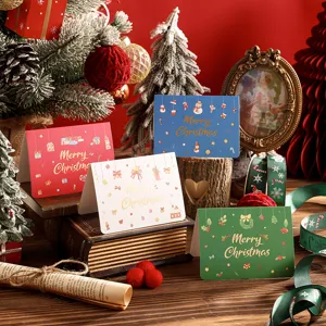 Detailed shot of Christmas greeting cards with gold foil lettering on a wooden table