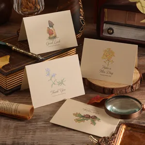 Set of vintage folded greeting cards featuring botanical floral illustrations on a rustic desk