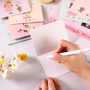 Primer plano de una mano escribiendo en una tarjeta de felicitación DIY de dibujos