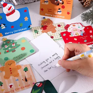 Detailed view of hand writing a holiday message on a cute cartoon Christmas greeting card