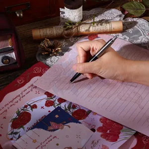 Close-up of vintage floral letter paper with rose and butterfly motifs being written on
