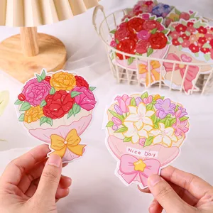 Gros plan de cartes de vœux en forme de bouquet tenues en main sous une lampe