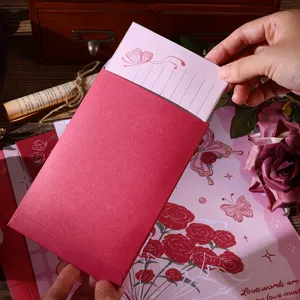 Detailed view of hand inserting vintage butterfly letter paper into a pink envelope