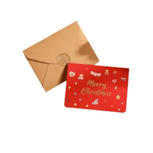 Carte de Noël rouge festive avec lettrage doré et enveloppe en kraft.