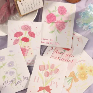 Vista macro detallada de tarjetas de felicitación florales con tipografía elegante en oro y rosa.