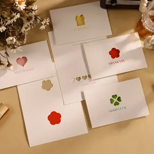 Nahaufnahme minimalistischer weißer Grußkarten mit ausgestanzten Herz- und Blumenmotiven