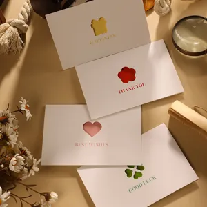 Nahaufnahme minimalistischer Grußkarten mit ausgestanztem Herz- und Blumendesign in warmem Licht