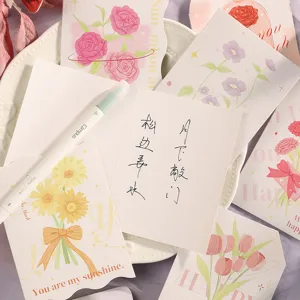 Primer plano de elegantes tarjetas de felicitación florales con notas manuscritas en un escritorio