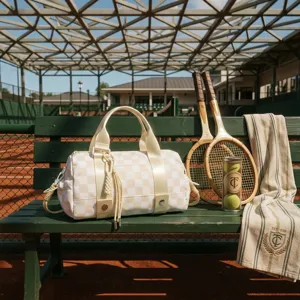 Elegante borsa da viaggio a scacchi crema e gialla su una panchina da tennis