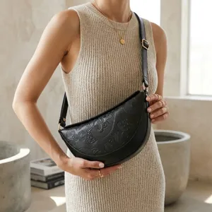 Detalle de bolso media luna negro grabado con textura paisley y correa ajustable