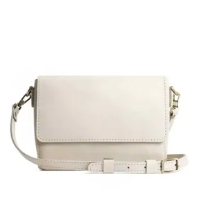 Primer plano de un bolso bandolera beige minimalista con herrajes dorados vintage
