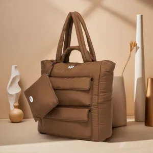 Detailweergave van de zachte bruine puffertextuur en het bijpassende etui van deze tas