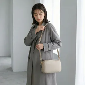 Vista detallada del bolso de cámara minimalista de cuero beige cruzado para mujer