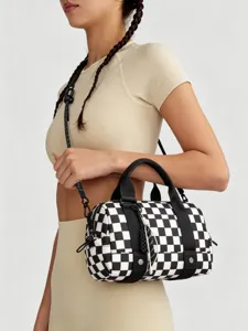 Primo piano di una borsa da viaggio a scacchi bianca e nera tenuta da una modella.