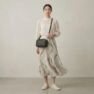Vista detallada de un bolso bandolera de cuero negro tipo cámara en una modelo asiática