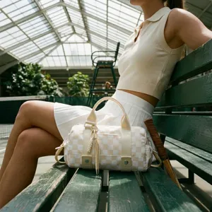 Elegante borsa da viaggio a scacchi presentata in un raffinato campo da tennis.