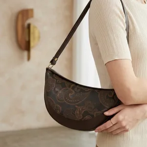 Detalle del bolso de media luna marrón vintage con relieve paisley y correa ajustable