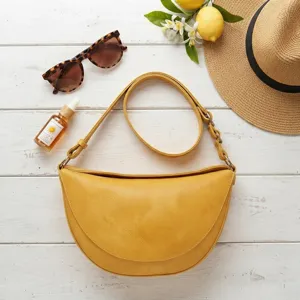 Detalle de un bolso bandolera amarillo vintage con relieve sobre fondo de madera blanca