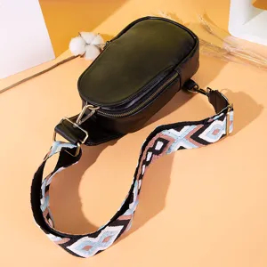 Detalle de un bolso de pecho de cuero sintético negro con correa de patrón bohemio vivo