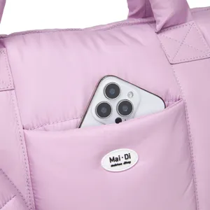 Detail van het buitenvak van een roze gewatteerde tas met ruimte voor een smartphone.