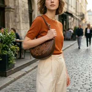 Bolso bandolera vintage de cuero marrón grabado llevado por una modelo en la calle.