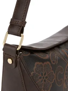 Primer plano de bolso de cuero marrón retro con relieve floral y herrajes dorados.