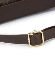 Detalle de una correa de bolso de cuero marrón ajustable con una hebilla de metal dorado.