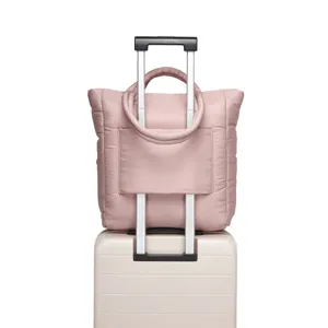 Detail van roze gewatteerde tas met bagagehoes bevestigd aan een kofferhandvat