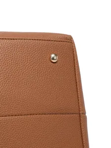 Detalle de la textura de cuero granulado marrón y perno dorado en bolso elegante