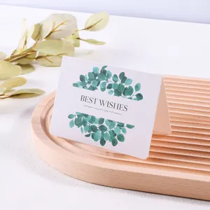 Wenskaart in bosstijl met groene bladeren en 'Best Wishes' tekst op een houten dienblad.