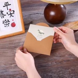 Primer plano de una mano sosteniendo un sobre vintage de papel kraft con tarjeta