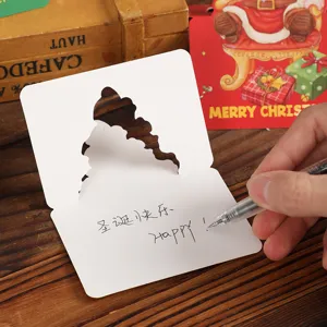 Close-up of hand writing a holiday message on a white die-cut Santa Christmas card