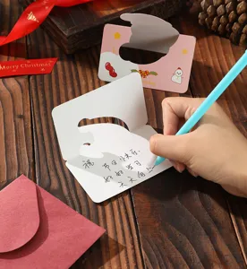 Detail view of writing a message on a die-cut Christmas greeting card with red envelope.