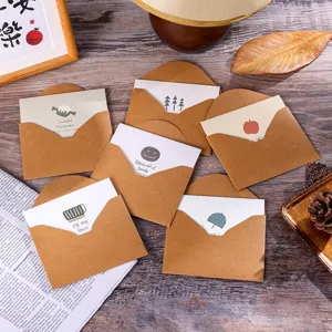 Primer plano de mini sobres de papel kraft vintage y tarjetas de felicitación en mesa