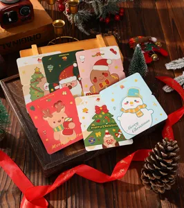 Detail view of various cartoon Christmas greeting cards on a festive wooden background.