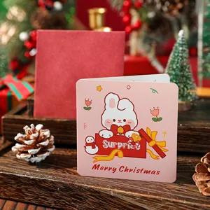 Nahaufnahme einer rosa Weihnachtskarte mit süßem Hasen- und Schneemann-Motiv.