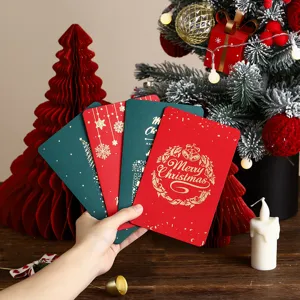 Detailansicht von handgehaltenen roten und grünen Weihnachtskarten mit Goldfolienprägung.