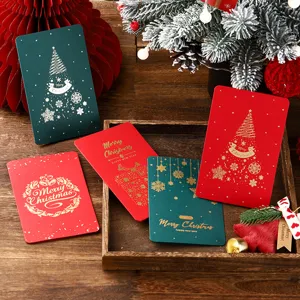 Detaillierte Makroansicht von roten und grünen Weihnachtskarten mit Goldfolie auf Holztablett