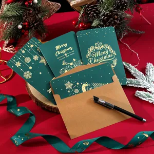 Primer plano de tarjetas de Navidad verdes con estampado dorado y sobre de papel kraft.