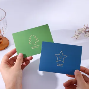 Elegant gold foil greeting cards with minimalist star and tree designs held by hands