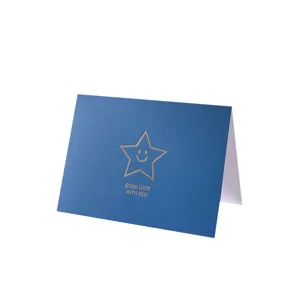Blue minimalist greeting card with gold-stamped star and "Good Luck" message on white background.