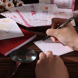 Close-up of a person writing on a floral postcard with aesthetic flower designs