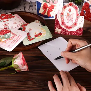 Detailansicht einer Hand, die auf eine vintage Rosen-Blumen-Grußkarte schreibt