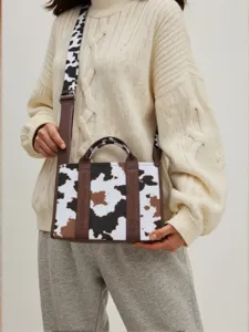 Detalle de un bolso de mano bohemio con estampado de vaca y correa ancha a juego estilosa.