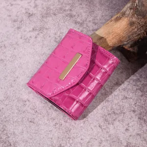 Vista detallada de la cartera rosa brillante con textura de cocodrilo y detalles