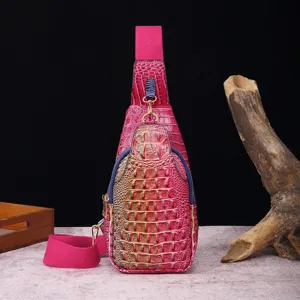 Vista detallada del bolso de pecho magenta con relieve de cocodrilo y correa ancha