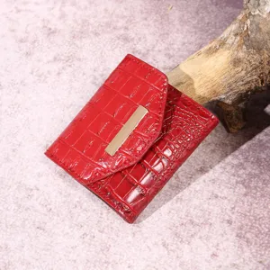 Vista detallada de la cartera roja para mujer con textura de cocodrilo y barra metálica dorada